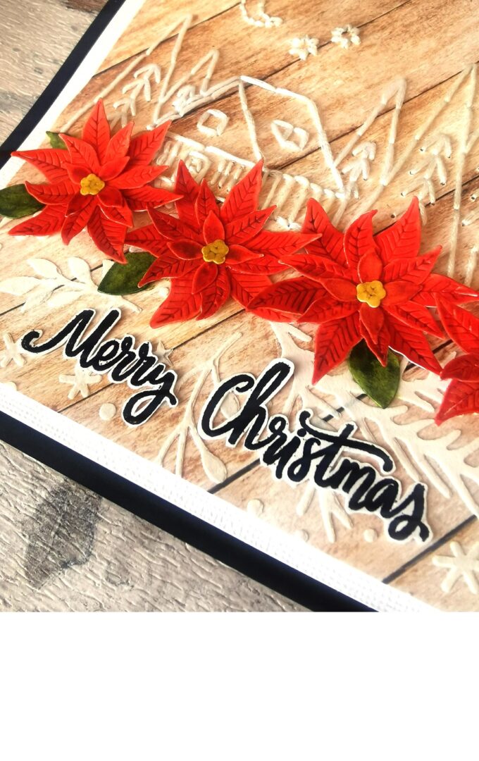 Carte de noël en scrapbooking avec un village brodé et des poinsettias