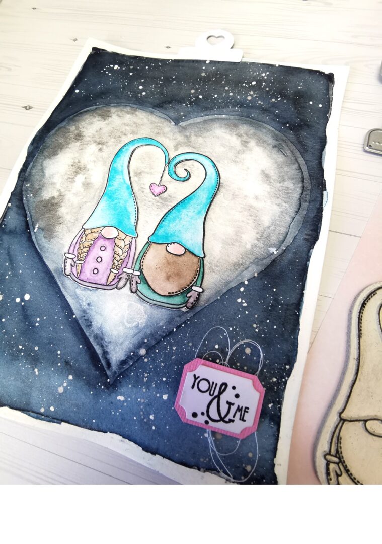 carte en scrapbooking avec deux petits gnomes devant une lune en forme de coeur